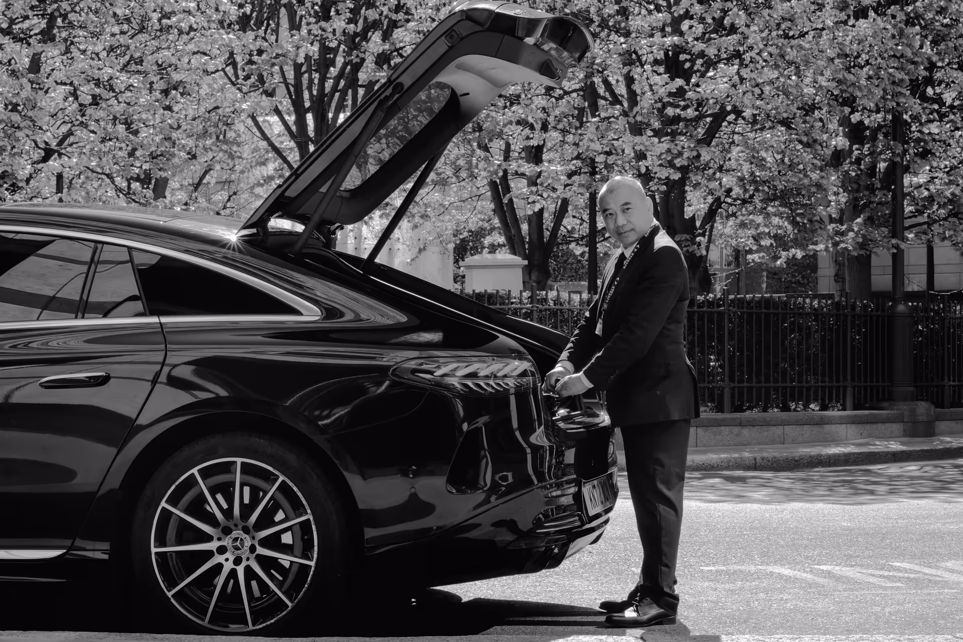 Professional chauffeur standing beside a premium vehicle